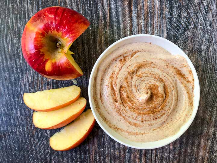 red apple and slices with a white bowl of cinnamon toast cashew cream cheese spread