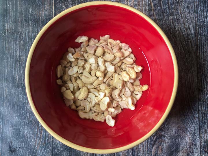 red bowl with raw cashews covered in water