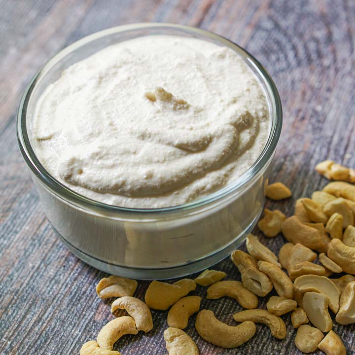 glass bowl with low carb cashew cream cheese and scattered cashews