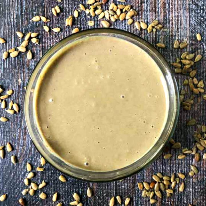 glass bowl with plain sunflower seed butter and seeds scattered around