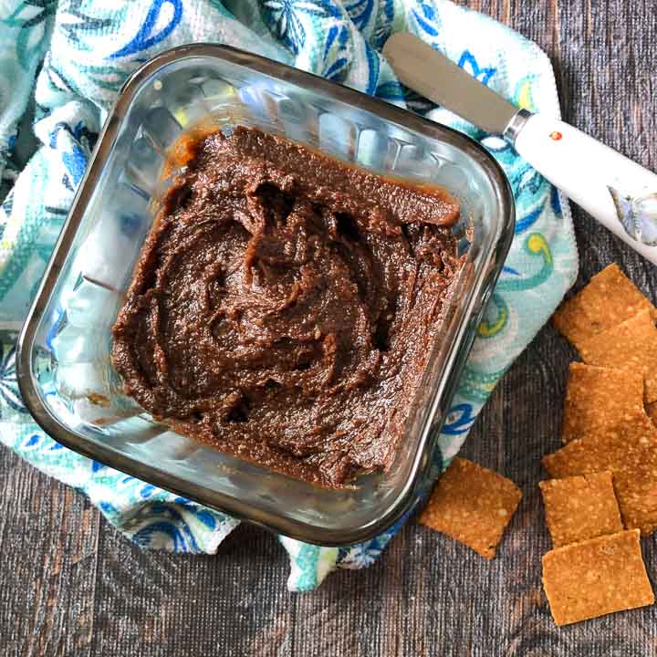 glass dish with keto chocolate sunflower seed butter and a spreader and crackers