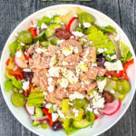 Aerial view of white bowl with Greek tuna salad with text overlay.
