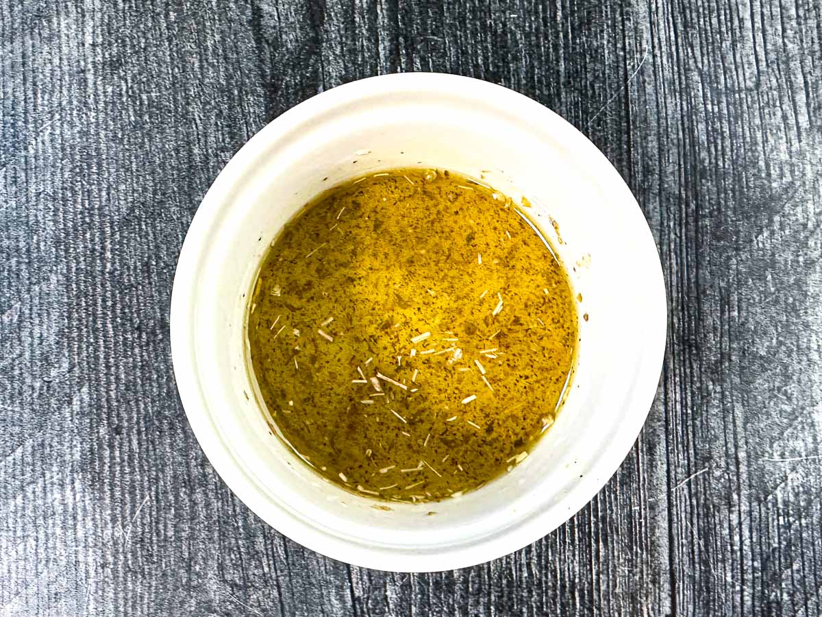 Aerial view of white ramekin with the Greek dressing.