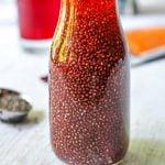 Bottle of red chia seed drink with a straw.