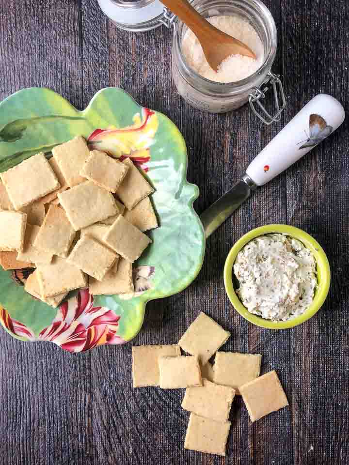 aerial view of a floral dish with almond thin crackers and a little green bowl with cream cheese spread