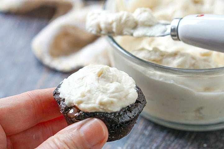 hand holding a keto chocolate muffin with low carb cream cheese frosting