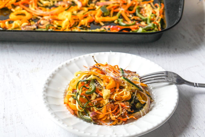 Veggie noodles on a plate with a baking tray in the background.