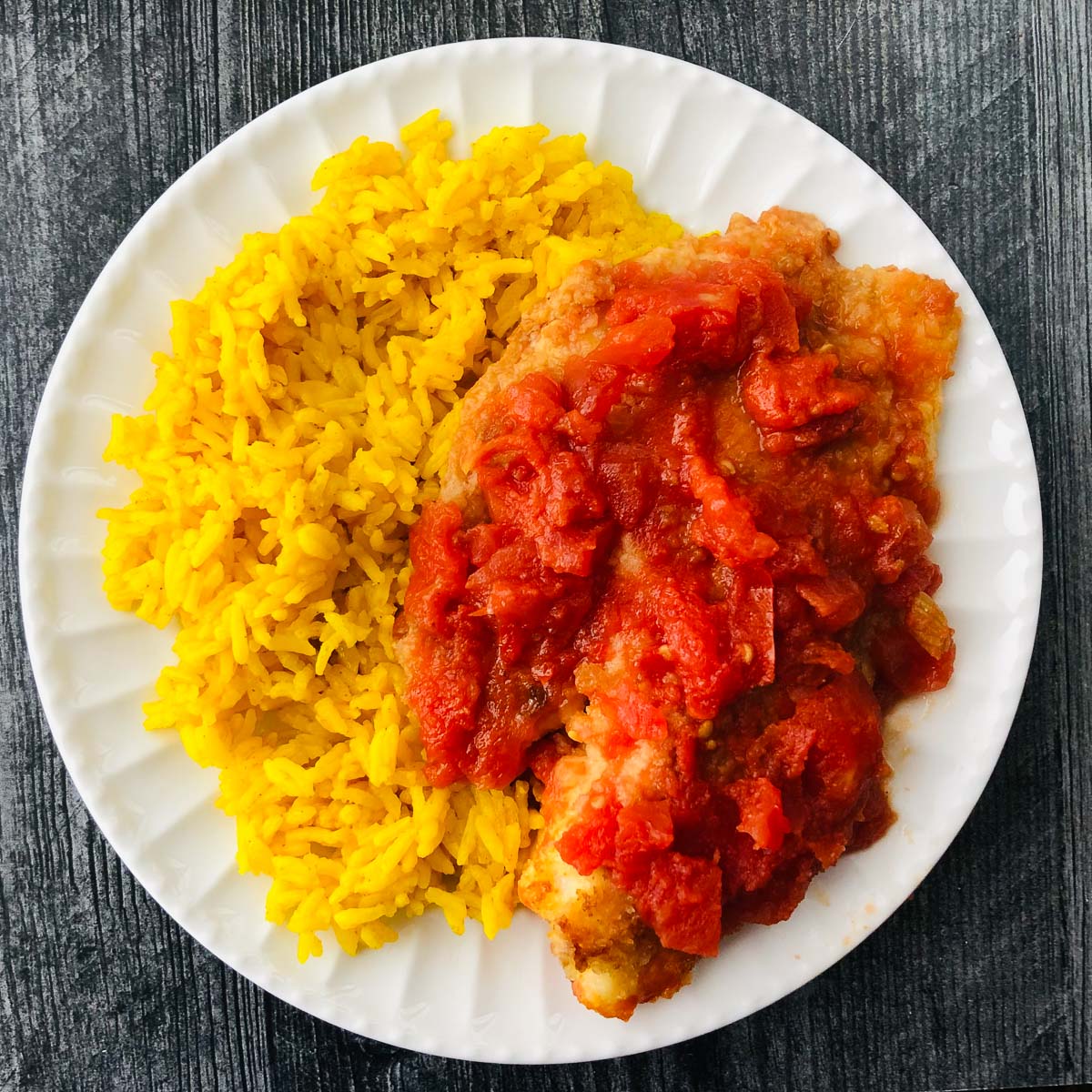 white plate with rice and stew tomato tilapia