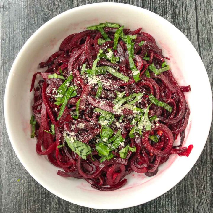white bowl with beet noodles and fresh basil