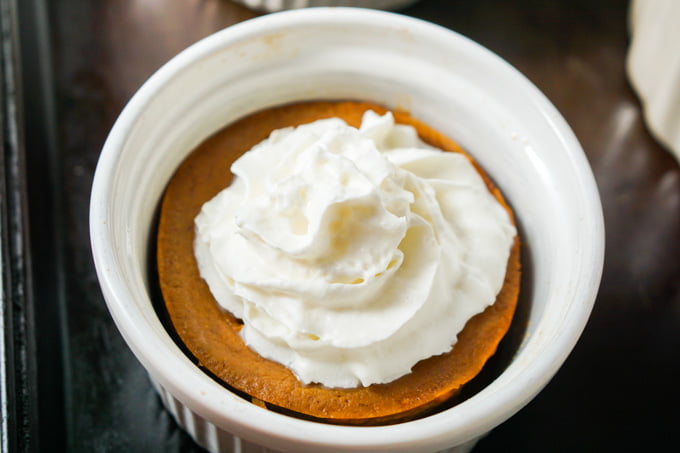 closeup of 4 white ramekins with mini low carb pumpkin pie with whipped cream on top