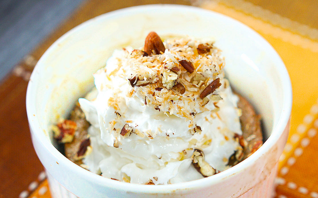 closeup of a ramekin of pumpkin pie with whipped cream and nuts