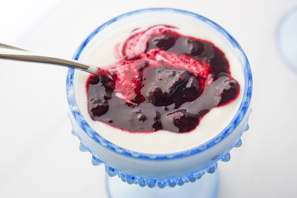 blue glass bowl with coconut yogurt with sugar free blueberry sauce on top