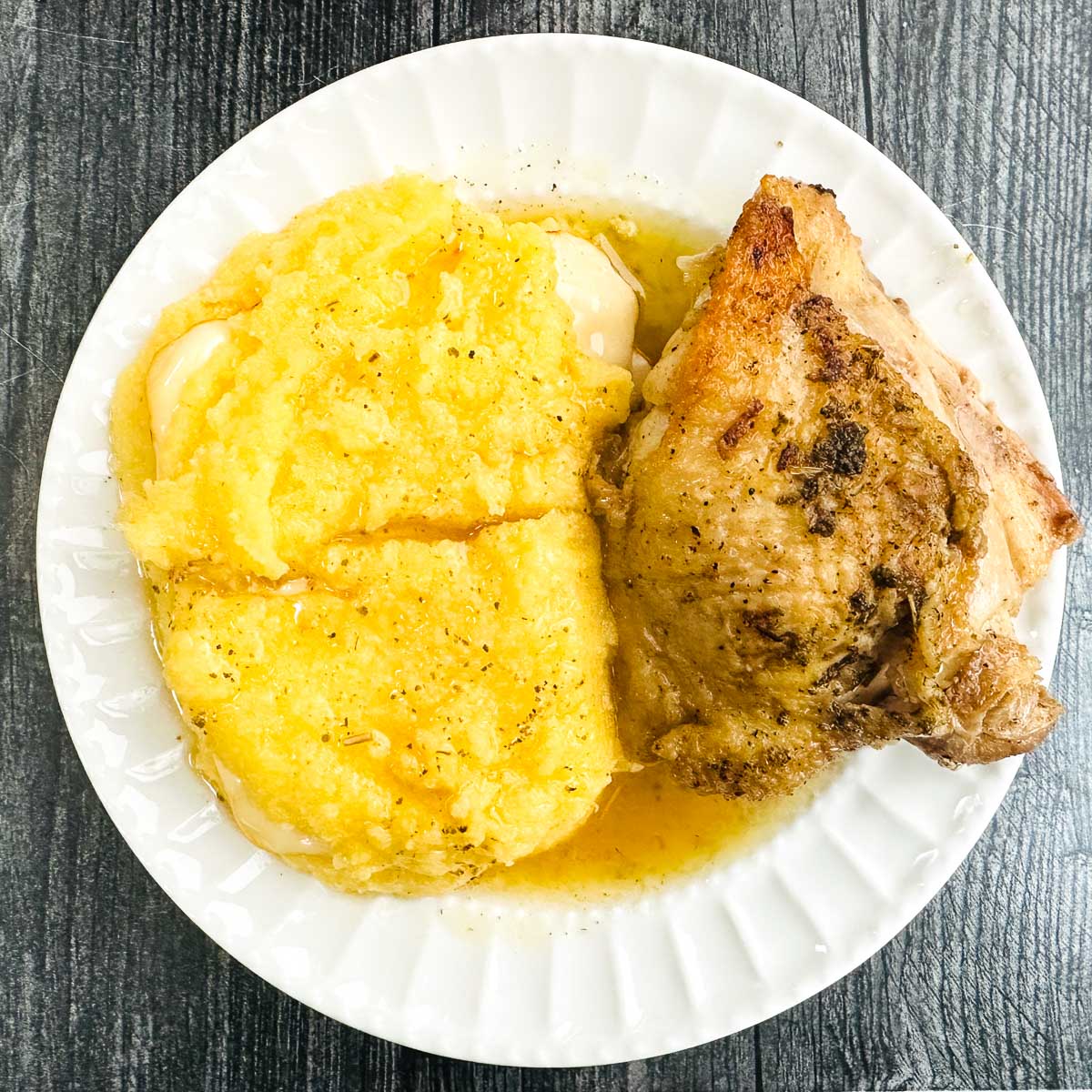 aerial view of a white plate with chicken and polenta