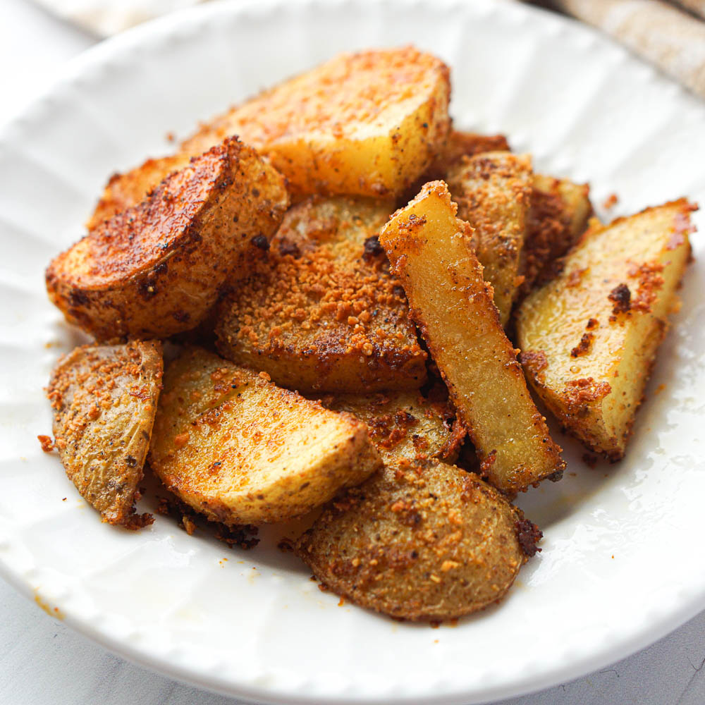 closeup of spicy roasted potatoes on a white plate