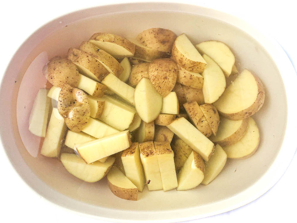 baking dish with raw potato pieces covered in water