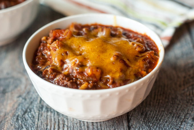 closeup of a bowl of chili with melted cheddar cheese