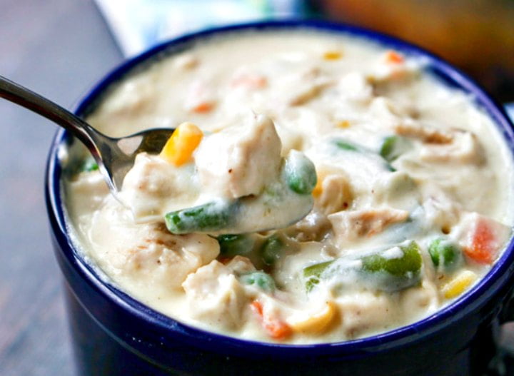 closeup up fo a spoonful of low carb chicken pot pie soup in dark blue mug