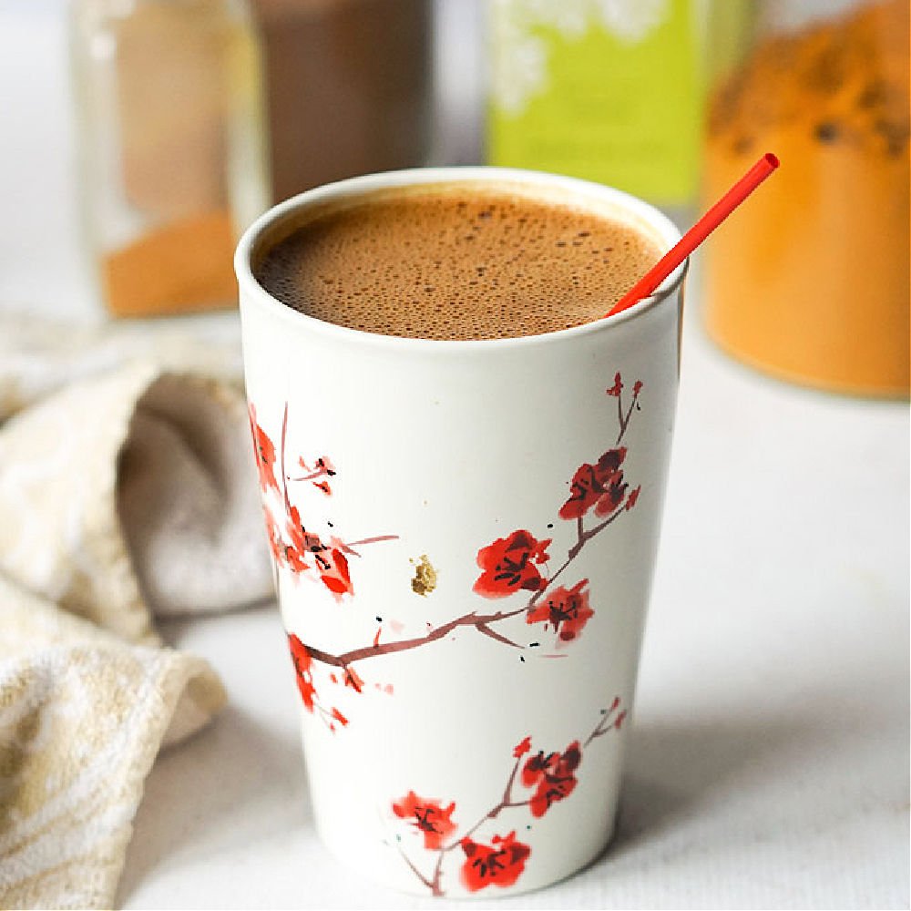white mug with red flowers with mocha maca matcha drink