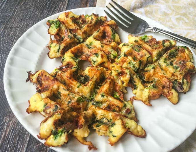 white plate with 3 savory keto waffles with a fork and tea towel in background