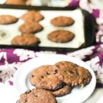 cookie sheet with keto chocolate chip cookies on purple towel with text overlay