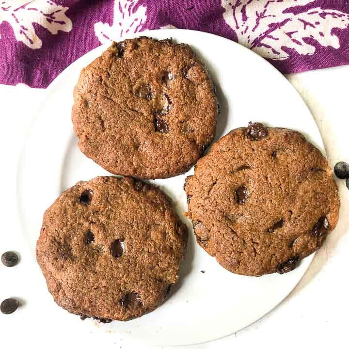 white plate with 3 keto 5 ingredient cookies and scattered chocolate chips