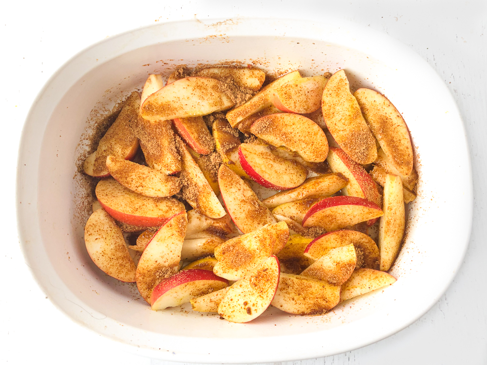 baking dish with raw fruit slices covered in coconut sugar