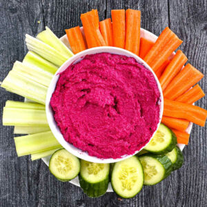 lemon beet hummus on a plate with cut veggies