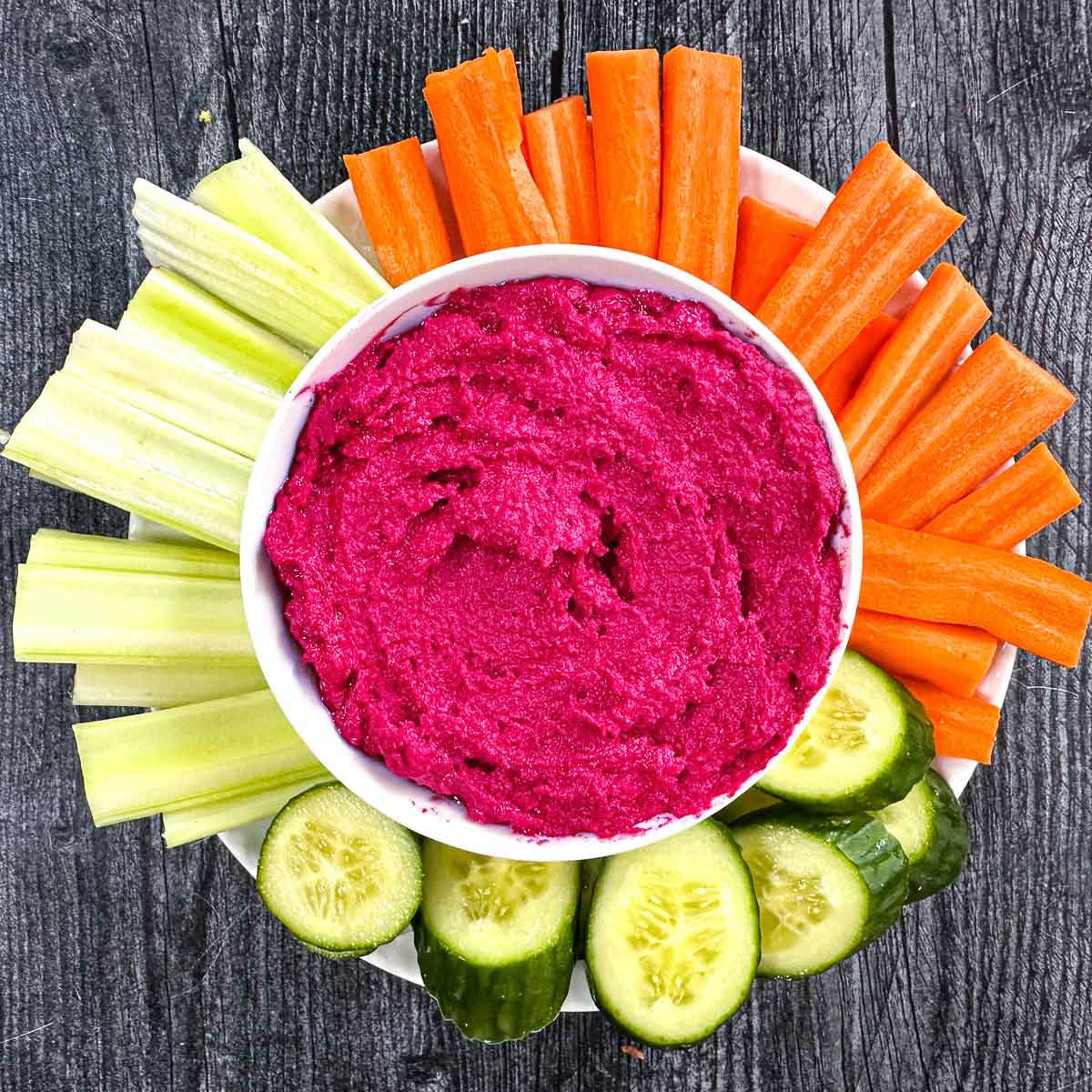 lemon beet hummus on a plate with cut veggies