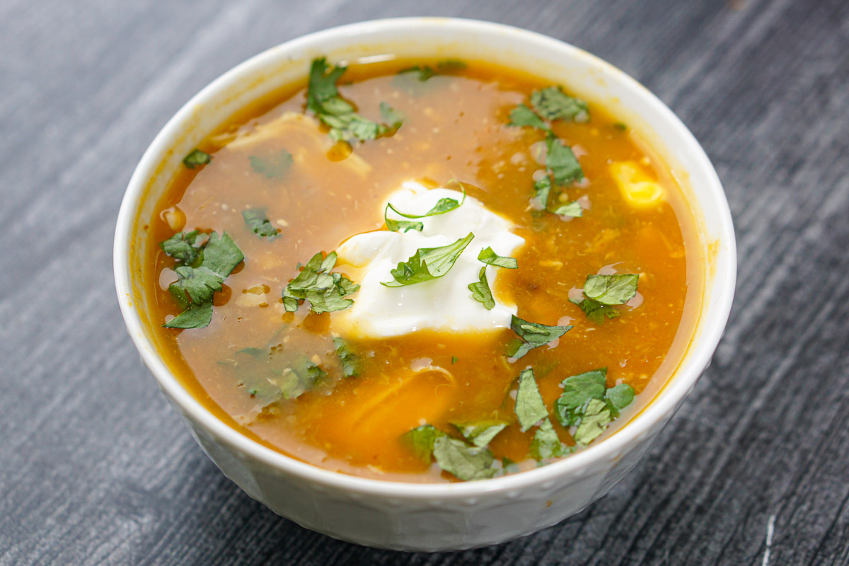 a bowl with finished soup topped with cilantro and sour cream