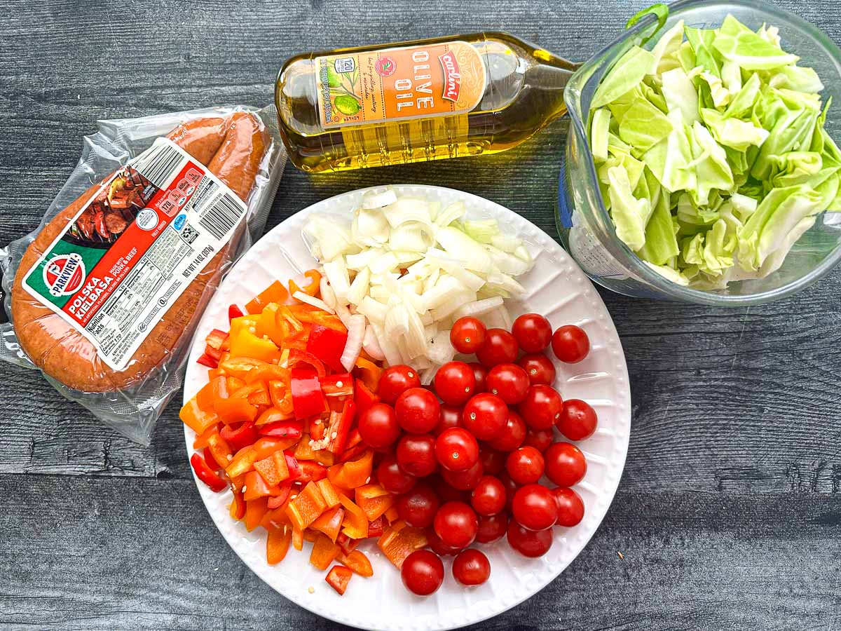recipe ingredients - onions, grape tomatoes, cabbage, bell peppers, olive oil, kielbasa