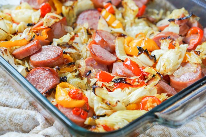 baking dish with kielbasa casserole with cabbage, peppers, tomatoes and onions.