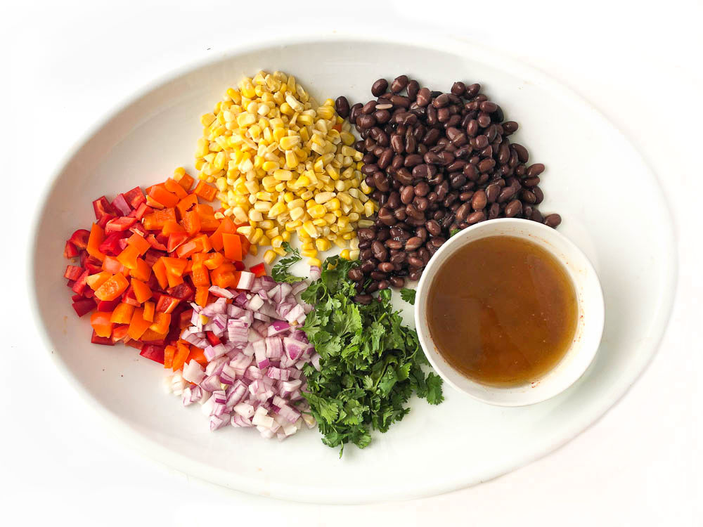 ingredients use for picnic salad - black beans, corn, peppers, onions, cilantro and bowl of dressing