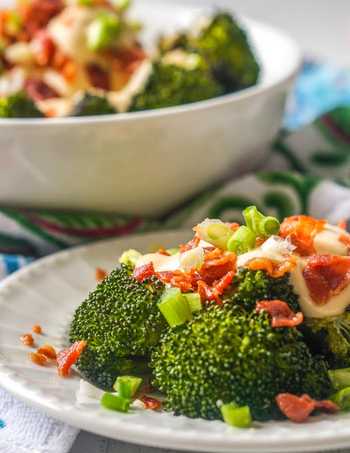 white bowl with broccoli and white plate with broccoli and cheese sauce