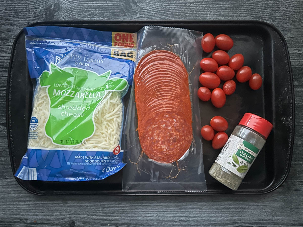 Recipe ingredients - pepperoni, mozzarella cheese, grape tomatoes and Italian seasoning.
