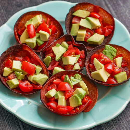 Aqua plate with 6 keto salami cups with avocado and tomatoes.