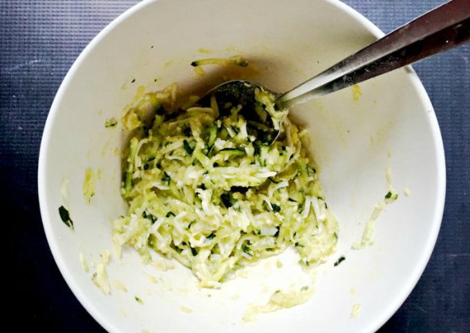 a bowl with the raw zucchini waffle mixture and a spoon