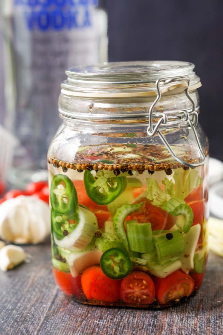 jar with Bloody Mary infused vodka in a jar and a bottle of vodka in the background 