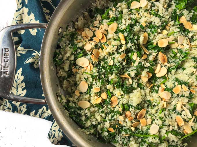 pan with spinach cauliflower rice pilaf and green tea towel underneath