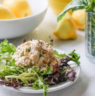 white plate with lettuce and low carb chicken salad with herbs and lemons in a bowl
