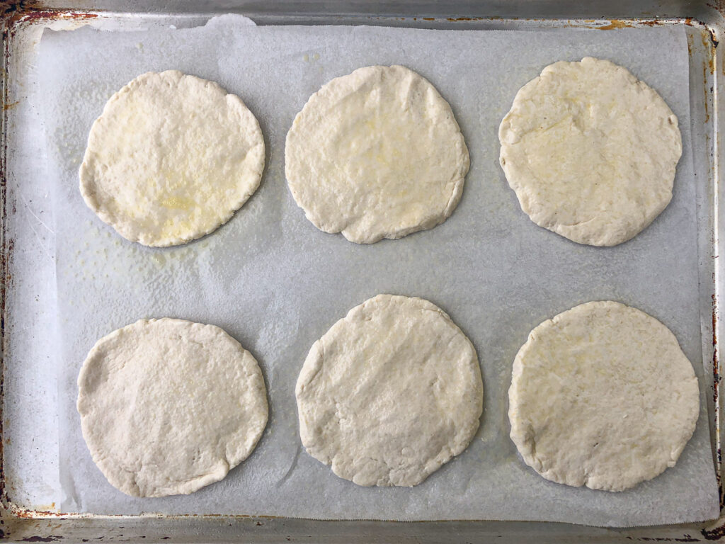 baking tray with 6 mini pizza crusts ready to bake