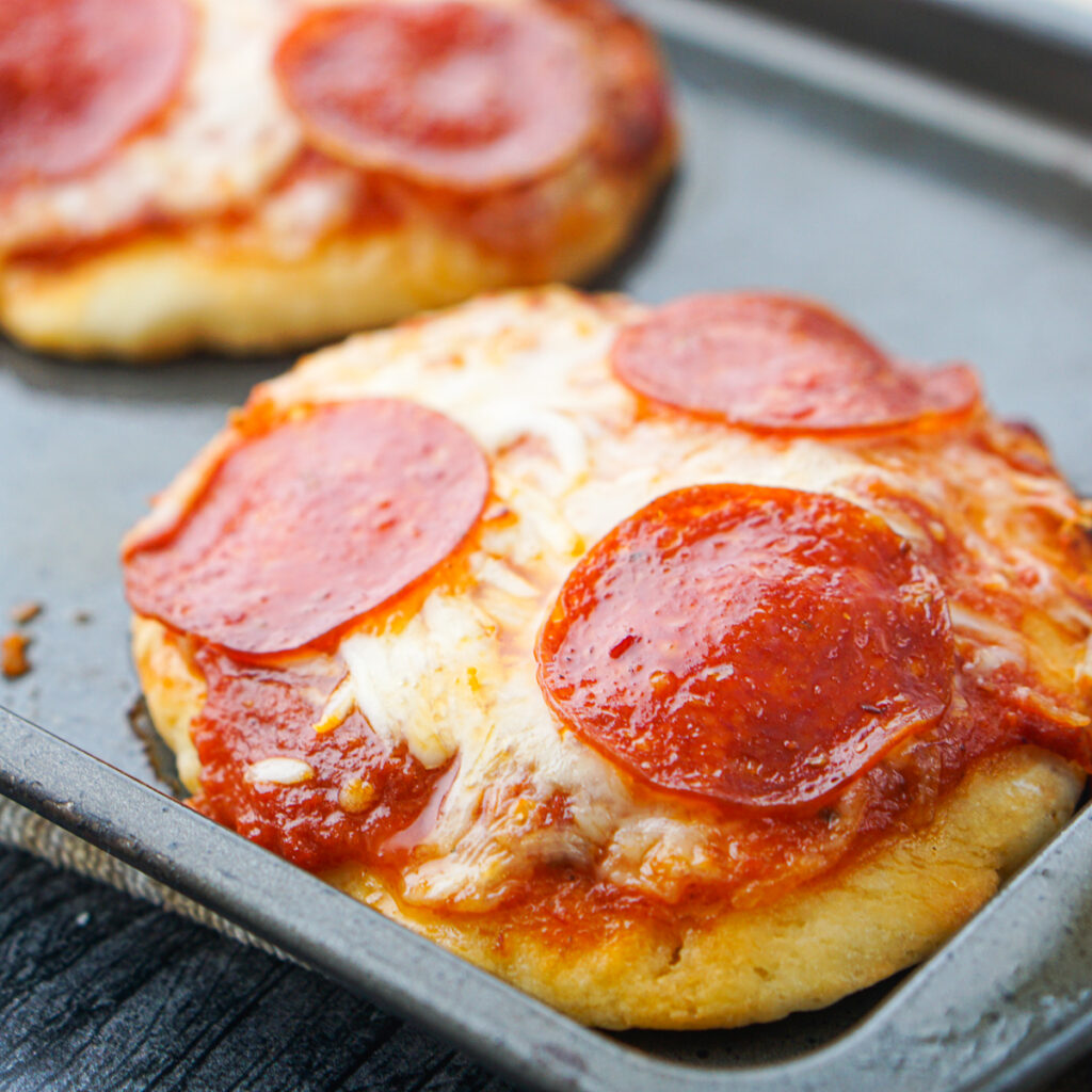 closeup of mini pepperoni pizzas made from 2 ingredient pizza dough on a baking tray