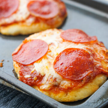 closeup of mini pepperoni pizzas on a baking tray