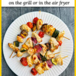 White plate with a skewers of keto Greek Chicken kabobs and text overlay.