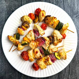 White plate with a skewers of keto Greek Chicken kabobs.