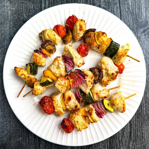White plate with a skewers of keto Greek Chicken kabobs.