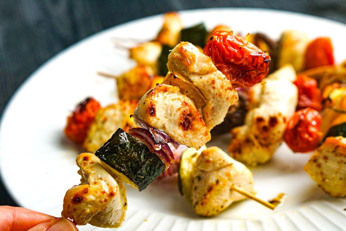 Fingers holding up a finished skewer.