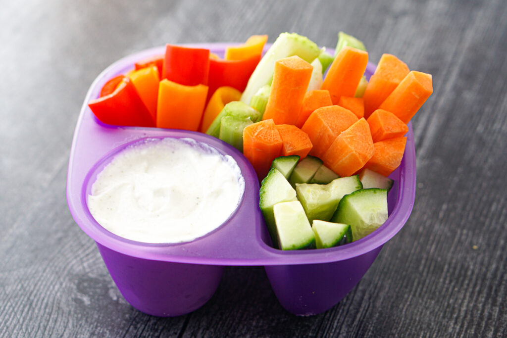 fun purple container holding both dip and cut veggies