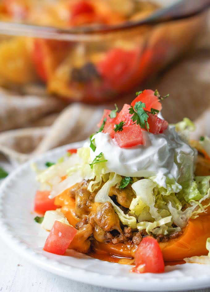 closeup of a taco stuffed pepper with lots of topping and baking dish in the background