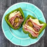 Aqua plate with an antipasto stuffed raw pepper cut in half.
