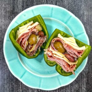 Aqua plate with an antipasto stuffed raw pepper cut in half.